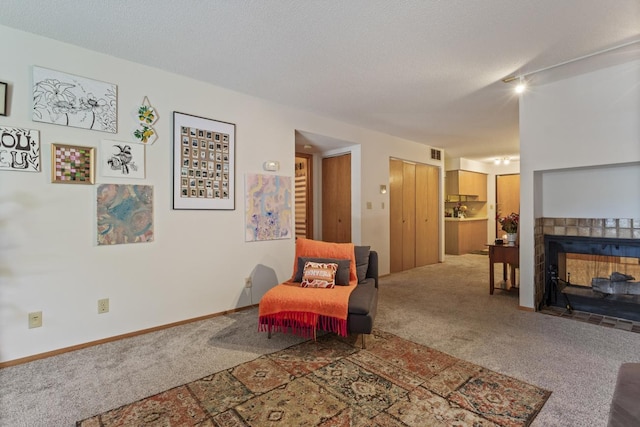 living room with carpet flooring, a tiled fireplace, and a textured ceiling