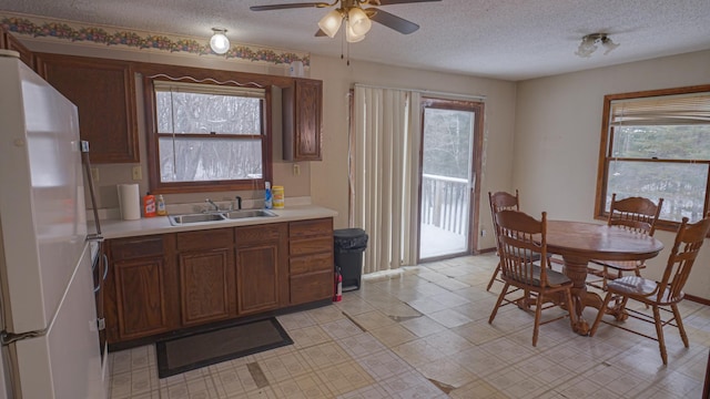 kitchen featuring a wealth of natural light, freestanding refrigerator, light countertops, and a sink