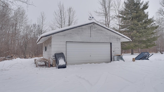 snow covered garage with a detached garage