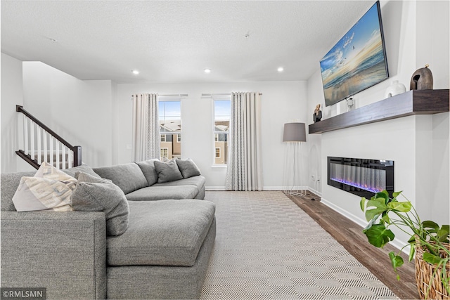 living area featuring a glass covered fireplace, baseboards, recessed lighting, and wood finished floors