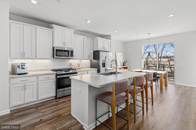 kitchen featuring appliances with stainless steel finishes, a kitchen island with sink, light countertops, white cabinetry, and a sink