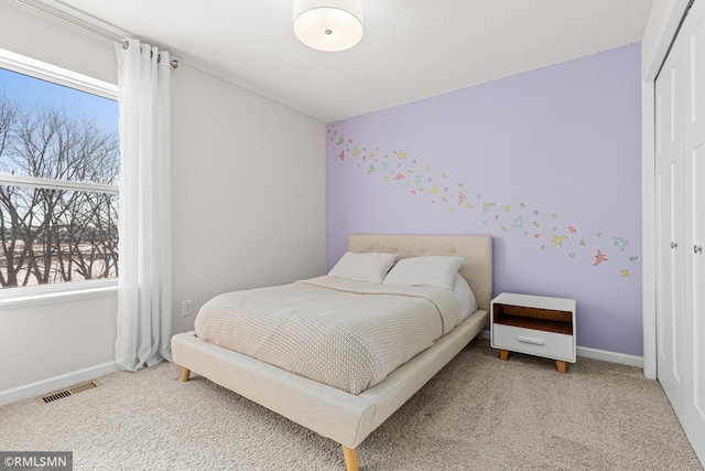 bedroom with carpet floors, baseboards, visible vents, and a closet