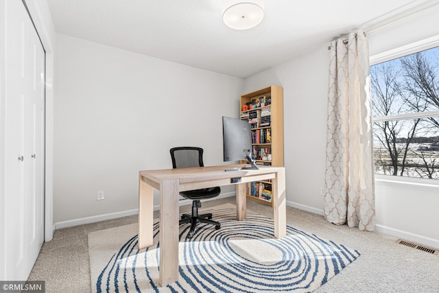 office area with visible vents, light colored carpet, and baseboards