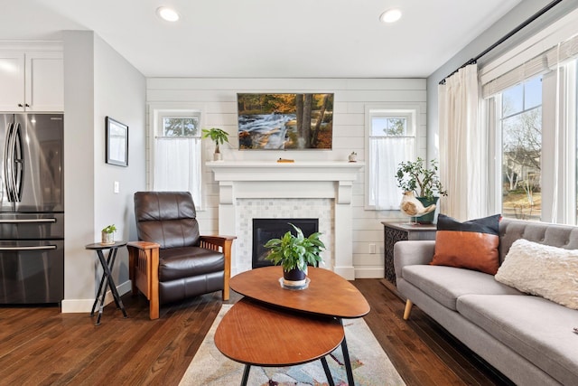 living room featuring a tiled fireplace, baseboards, dark wood-style flooring, and recessed lighting