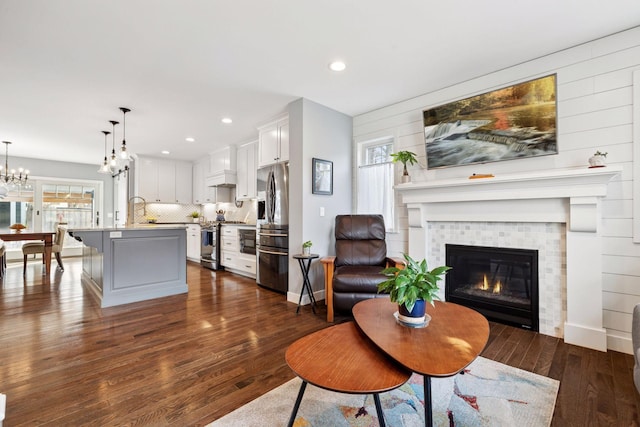 living room featuring a chandelier, dark wood finished floors, a tiled fireplace, and recessed lighting