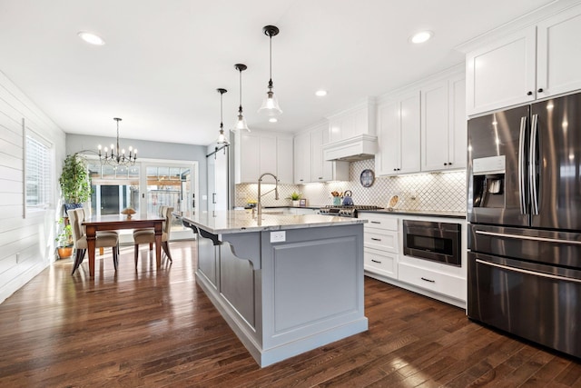 kitchen with stainless steel fridge, tasteful backsplash, dark wood-type flooring, light stone countertops, and white cabinetry