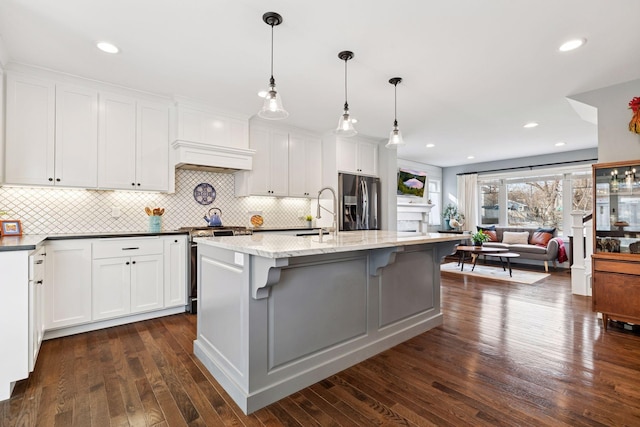 kitchen with a sink, white cabinets, appliances with stainless steel finishes, dark stone countertops, and dark wood finished floors