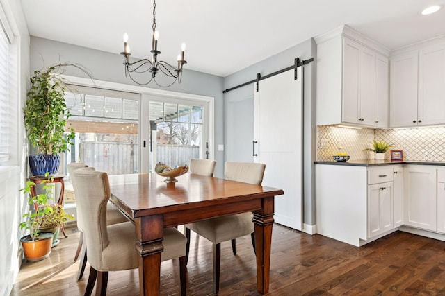 dining room with recessed lighting, dark wood-style flooring, an inviting chandelier, and a barn door