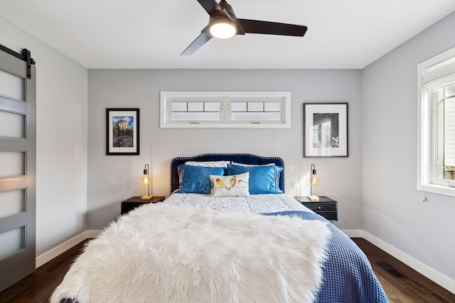 bedroom featuring dark wood-style floors, ceiling fan, baseboards, and a barn door