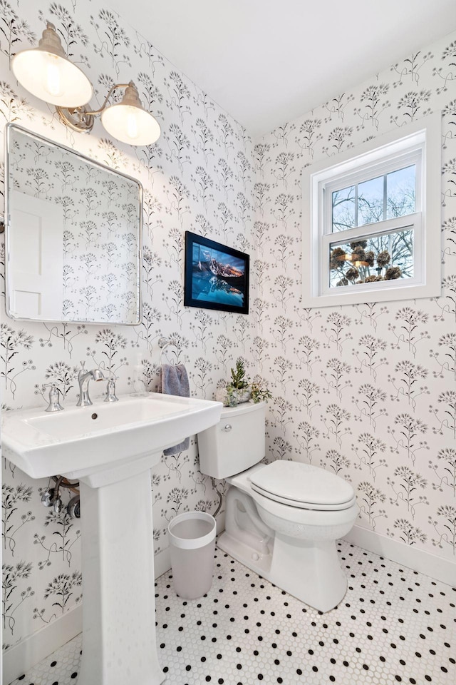 bathroom with toilet, a sink, tile patterned flooring, baseboards, and wallpapered walls