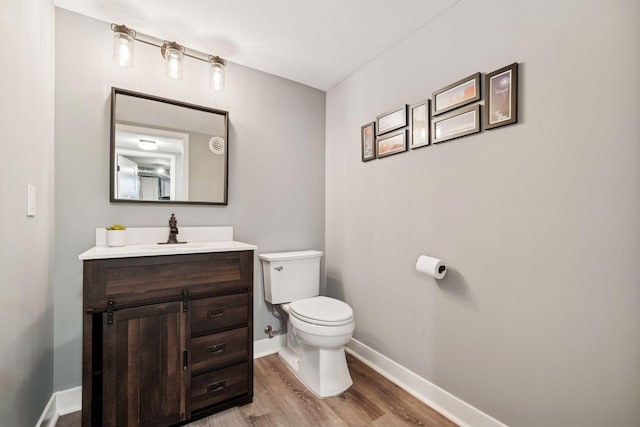 bathroom featuring baseboards, vanity, toilet, and wood finished floors