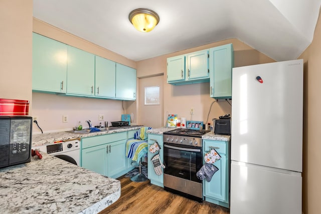 kitchen featuring washer / dryer, freestanding refrigerator, black microwave, a sink, and gas stove