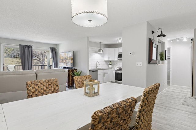 6213 Saint Croix Trl N Unit 102, Oak Park Heights, MN 55082 - dining room with light wood-type flooring, baseboards, track lighting, and a textured ceiling