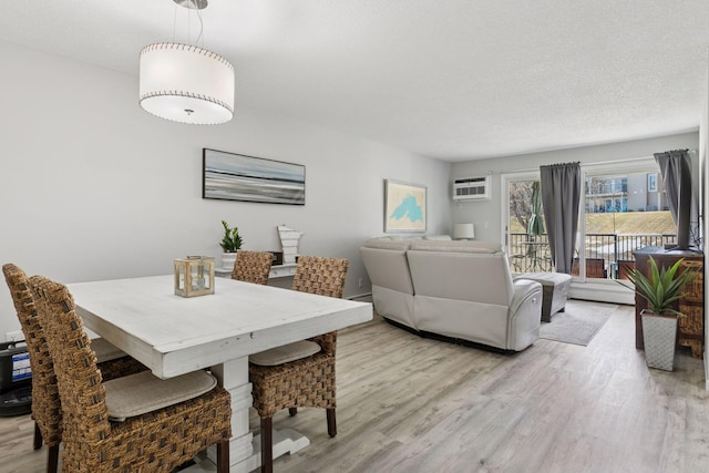 6213 Saint Croix Trl N Unit 102, Oak Park Heights, MN 55082 - dining room featuring light wood finished floors, a baseboard radiator, a wall mounted air conditioner, and a textured ceiling