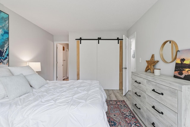 6213 Saint Croix Trl N Unit 102, Oak Park Heights, MN 55082 - bedroom with light wood-style floors, a barn door, and a closet