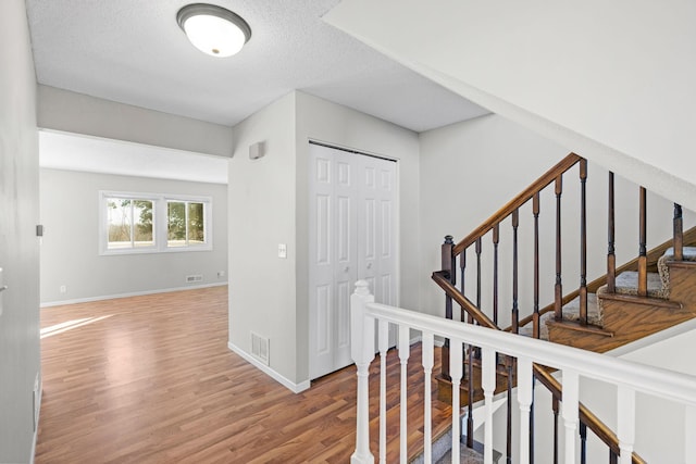 stairs with a textured ceiling and hardwood / wood-style flooring