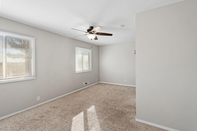 spare room with light carpet, ceiling fan, and a textured ceiling