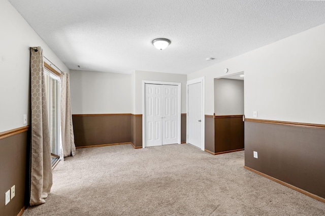 empty room with a textured ceiling and light colored carpet