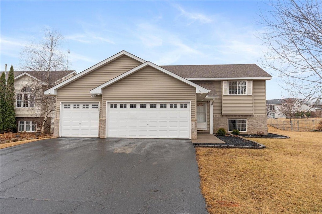 tri-level home featuring a front yard, roof with shingles, driveway, and an attached garage