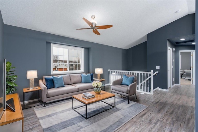 living room featuring vaulted ceiling, a textured ceiling, wood finished floors, and baseboards