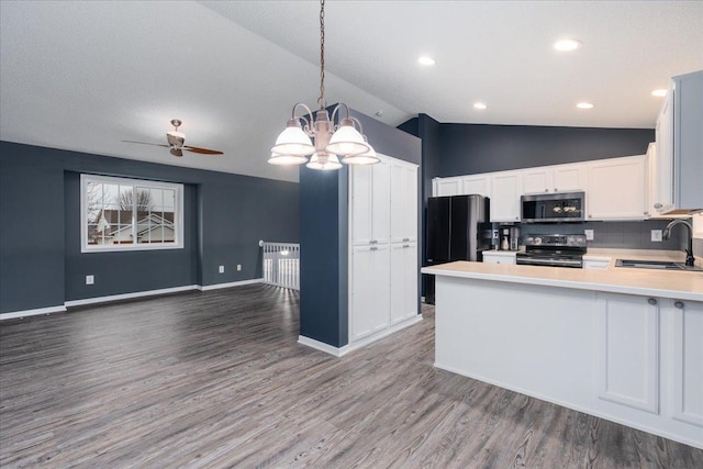 kitchen featuring stainless steel appliances, lofted ceiling, light countertops, open floor plan, and a sink