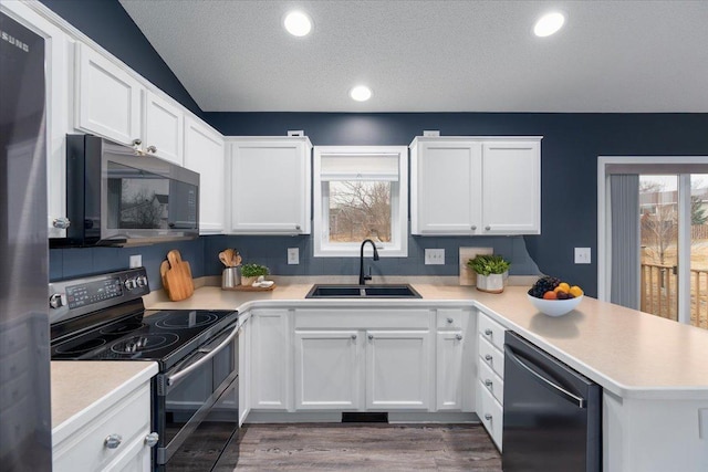 kitchen featuring black electric range, light countertops, a sink, a peninsula, and dishwashing machine