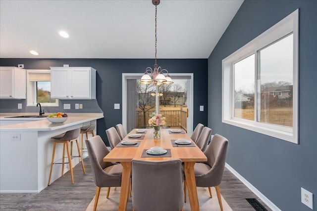 dining space with an inviting chandelier, visible vents, baseboards, and wood finished floors