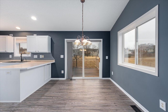 kitchen featuring white cabinetry, baseboards, light countertops, dark wood finished floors, and decorative light fixtures