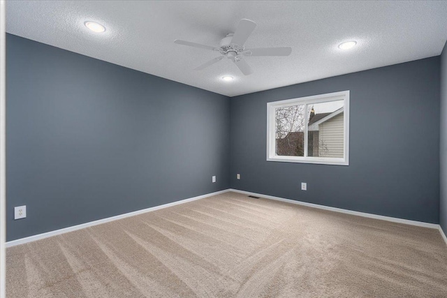 carpeted empty room with a ceiling fan, a textured ceiling, and baseboards