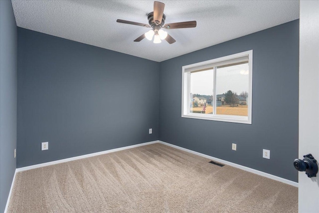 carpeted empty room featuring a textured ceiling, a ceiling fan, visible vents, and baseboards