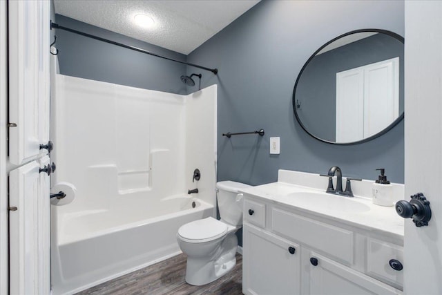 bathroom with toilet, vanity, wood finished floors, a textured ceiling, and shower / bathtub combination