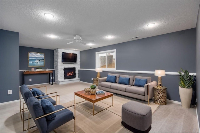 living area with baseboards, visible vents, a ceiling fan, a textured ceiling, and a stone fireplace