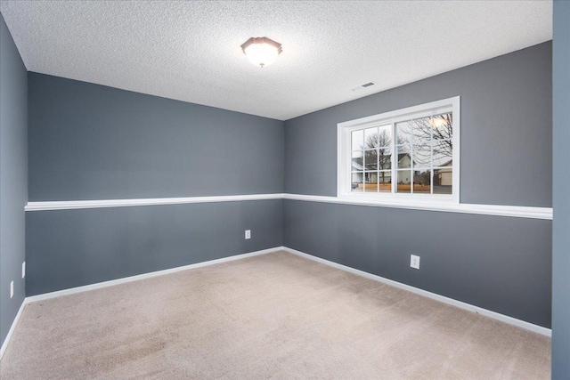 carpeted spare room featuring baseboards, visible vents, and a textured ceiling