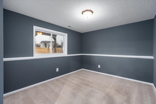 carpeted empty room featuring baseboards, visible vents, and a textured ceiling