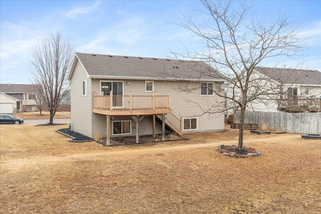 back of property with a deck, roof with shingles, stairway, and fence