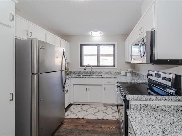 kitchen featuring white cabinetry, stainless steel appliances, dark hardwood / wood-style flooring, sink, and light stone counters