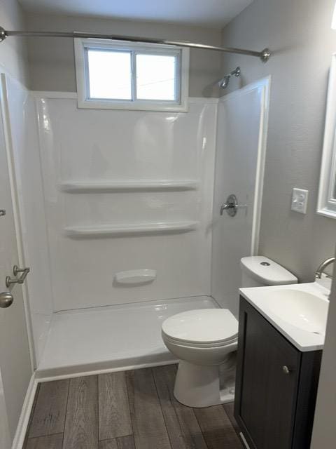 bathroom with toilet, hardwood / wood-style flooring, a shower, and vanity