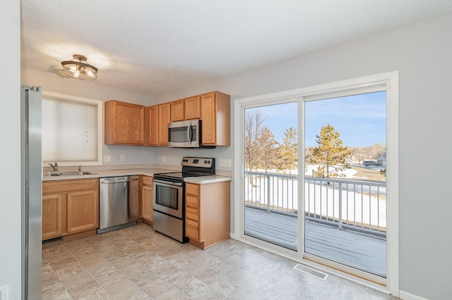 kitchen with visible vents, a sink, a textured ceiling, stainless steel appliances, and light countertops