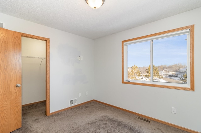 unfurnished bedroom featuring visible vents, carpet, a closet, and a walk in closet