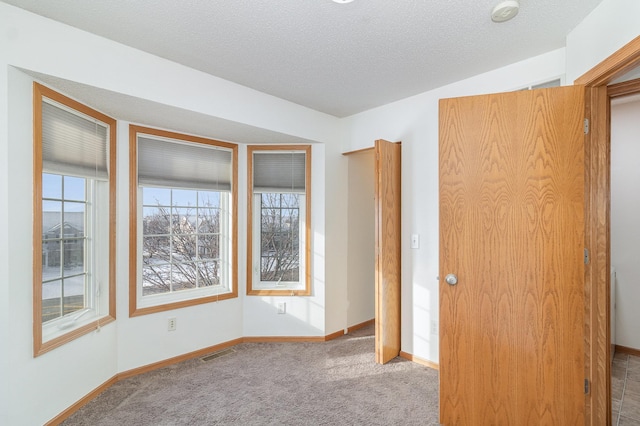 unfurnished room featuring visible vents, carpet, baseboards, and a textured ceiling