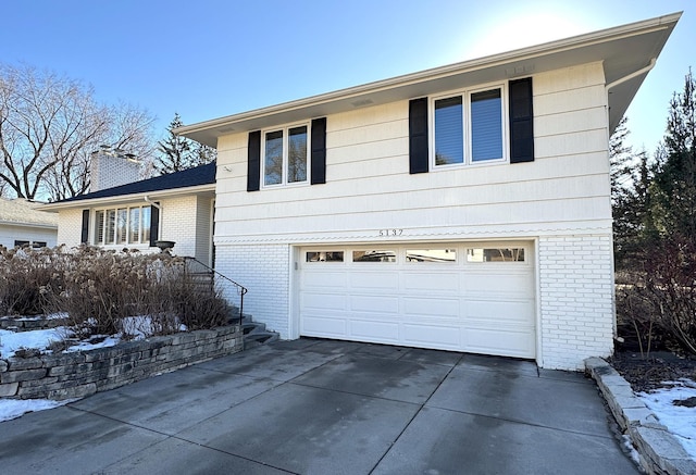 view of front of property featuring a garage, concrete driveway, brick siding, and a chimney