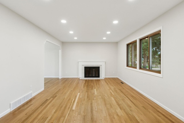 unfurnished living room featuring recessed lighting, a brick fireplace, light wood-style flooring, and baseboards