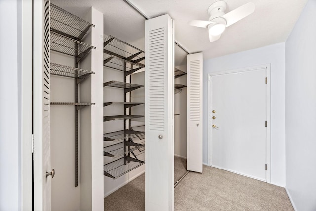 spacious closet with light carpet and ceiling fan