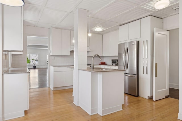 1625 25th St, Minneapolis, MN 55405 - kitchen with freestanding refrigerator, a sink, backsplash, light wood-type flooring, and white cabinets