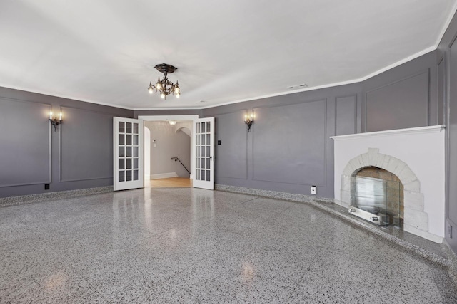 1625 25th St, Minneapolis, MN 55405 - unfurnished living room featuring french doors, a decorative wall, a fireplace with raised hearth, speckled floor, and a chandelier