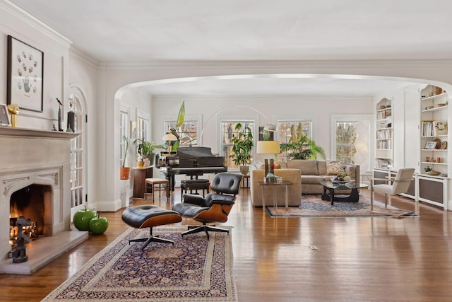 1625 25th St, Minneapolis, MN 55405 - living room featuring wood finished floors, ornamental molding, a high end fireplace, built in shelves, and arched walkways