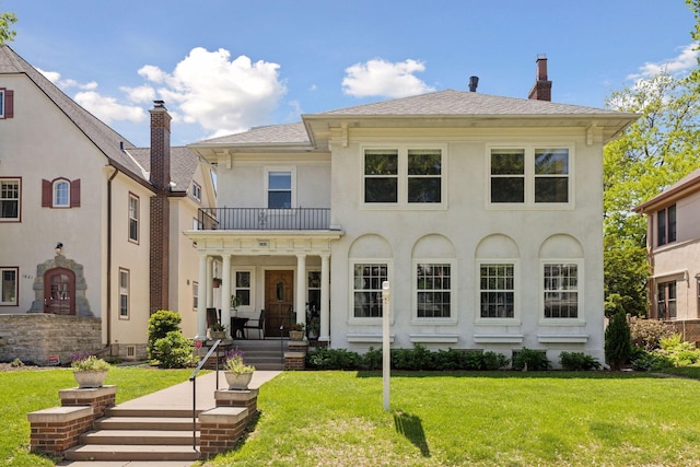 1625 25th St, Minneapolis, MN 55405 - view of front of property with a balcony, a chimney, a front yard, and stucco siding