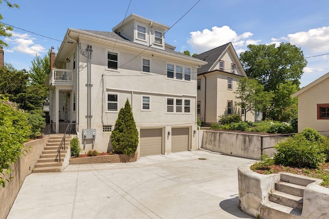 1625 25th St, Minneapolis, MN 55405 - view of front facade with stucco siding, concrete driveway, a garage, a balcony, and stairway