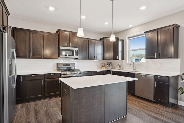 kitchen featuring stainless steel appliances, dark hardwood / wood-style flooring, decorative light fixtures, a kitchen island, and sink