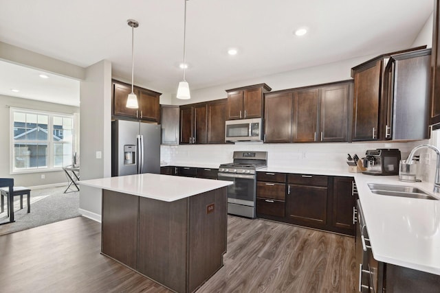 kitchen featuring sink, backsplash, stainless steel appliances, hanging light fixtures, and dark brown cabinets